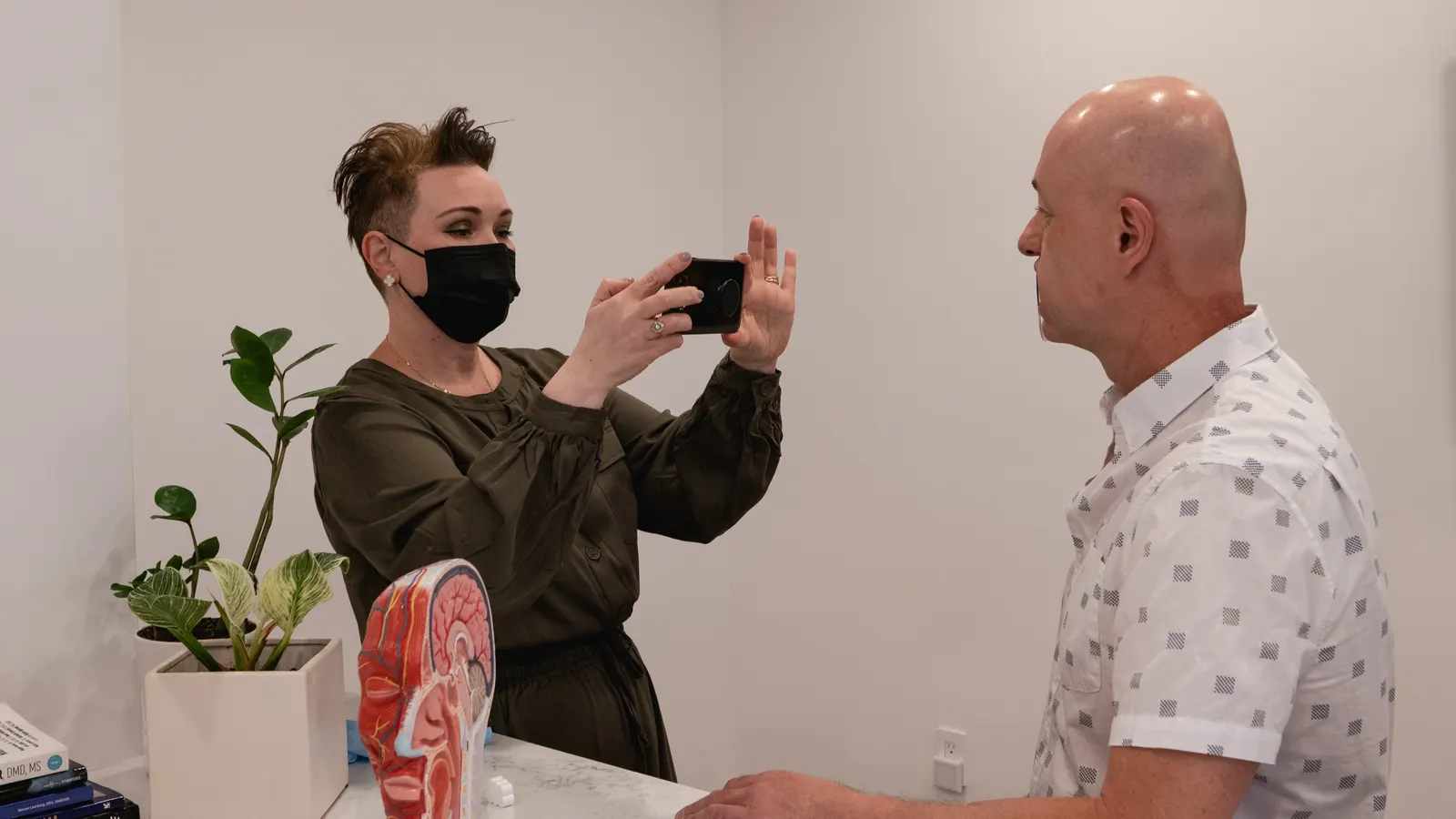 Julia Yarovoy photographing a client's facial profile during a myofunctional assessment